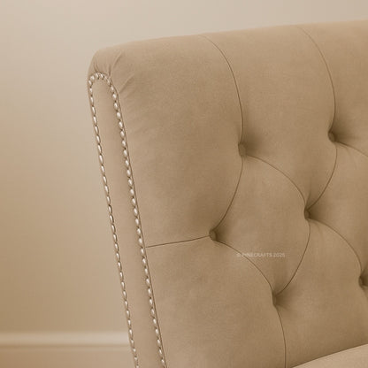Close-up of a beige upholstered headboard with tufted design and nailhead trim.