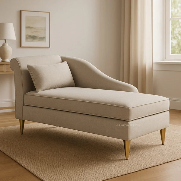 Beige chaise lounge in a living room setting with a lamp and framed picture.