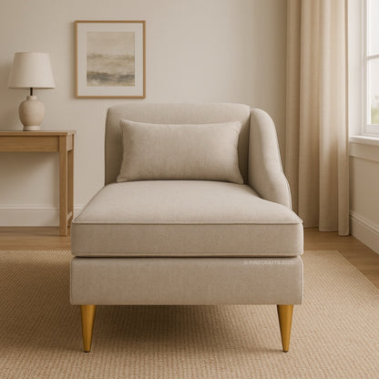 Beige armchair in a living room setting with a lamp and artwork on the wall.