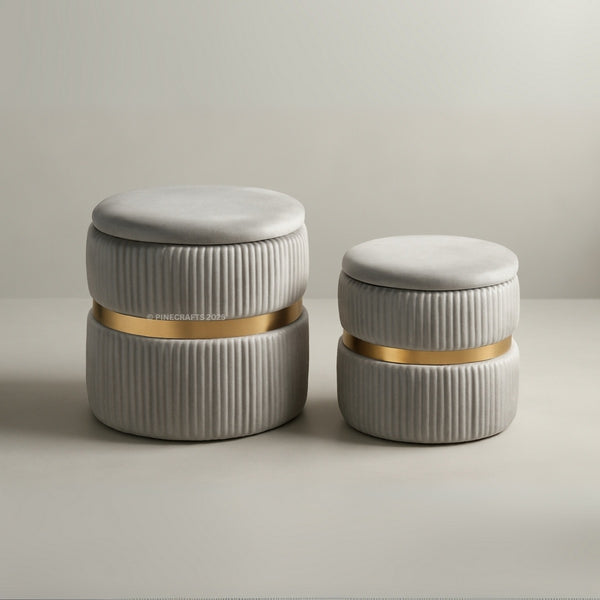 Two cylindrical ottomans with ribbed texture and gold bands on a neutral background