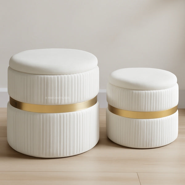 Two white ottomans with gold bands on a wooden floor.