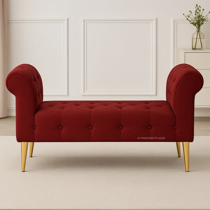 Red tufted bench with gold legs in a room with white walls and a vase.