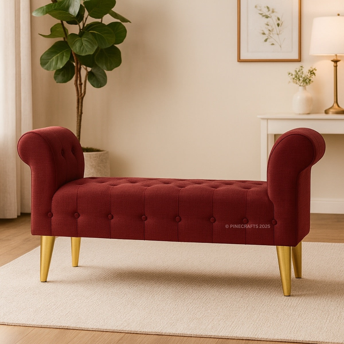 Red tufted bench with gold legs in a room with a plant and lamp.