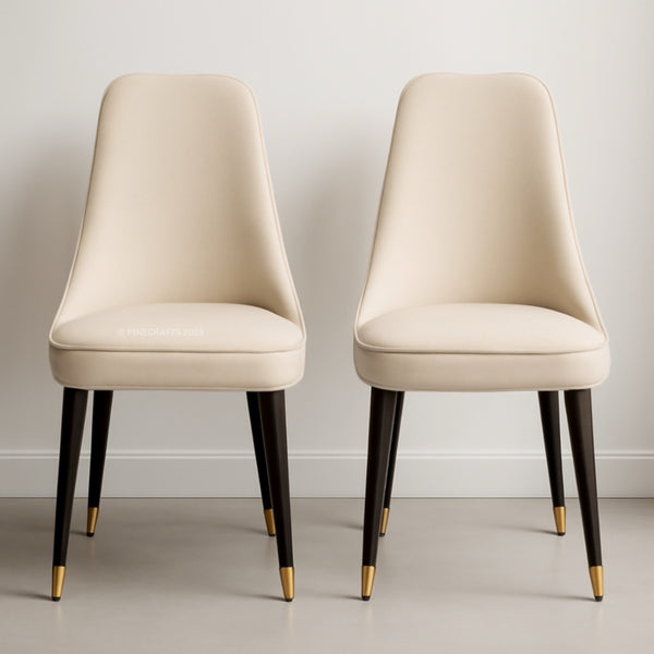 Two beige chairs with black legs and gold feet on a neutral background