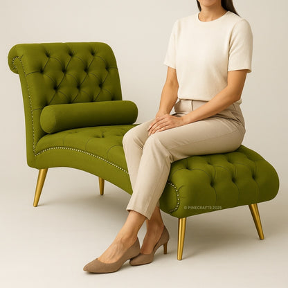 Woman sitting on a green tufted chair with gold legs against a plain background