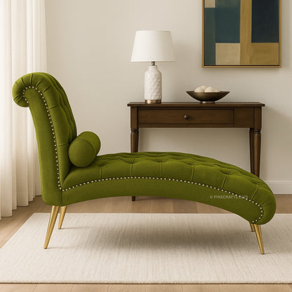 Green tufted chaise lounge in a room with a lamp and artwork on the wall.