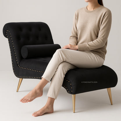 Person sitting on a black upholstered chair with gold legs against a plain background