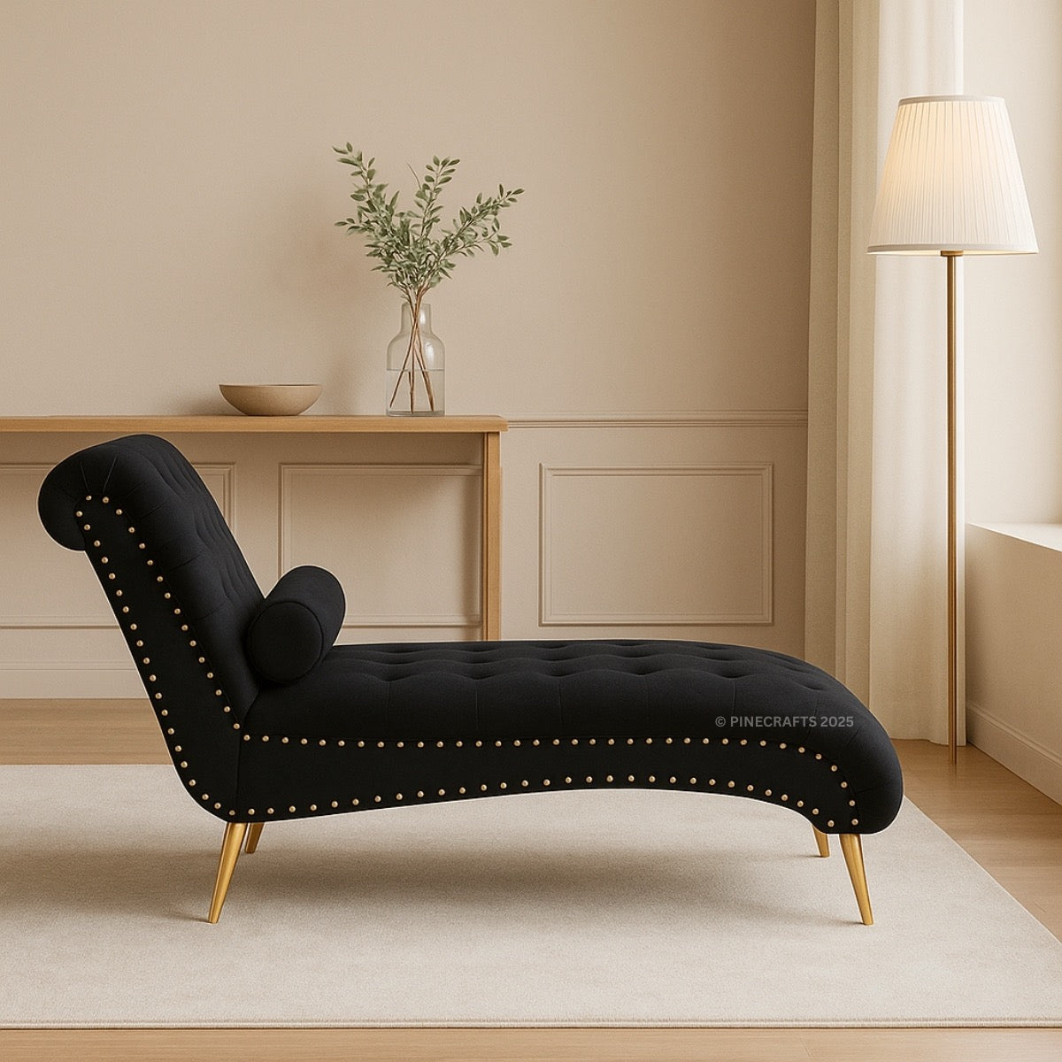 Black chaise lounge with gold accents in a room with a wooden table and lamp.