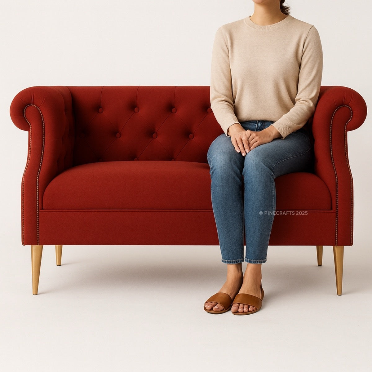 Person sitting on a red tufted sofa with a plain background
