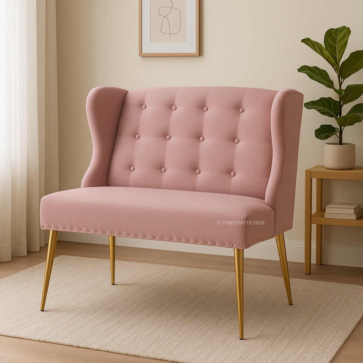 Pink tufted chair with gold legs in a room setting with a plant and side table.