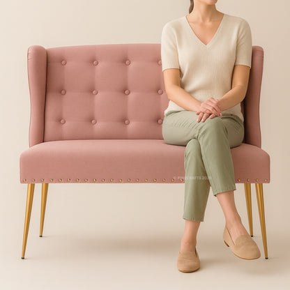 Person sitting on a pink tufted chair against a beige background