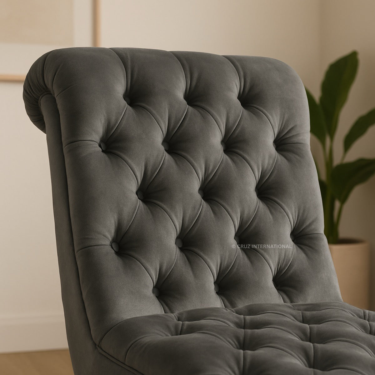 Gray tufted armchair in a room with a plant in the background