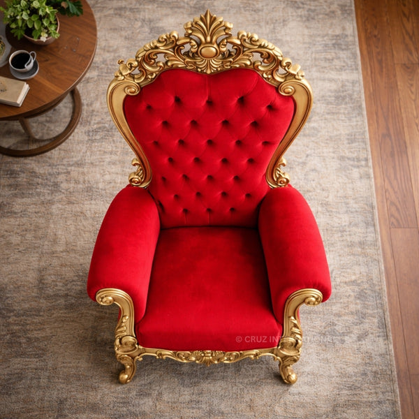 Red velvet chair with gold accents in a room setting