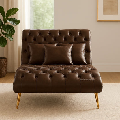 Brown leather sofa with tufted backrest and gold legs in a room with a plant and framed picture.