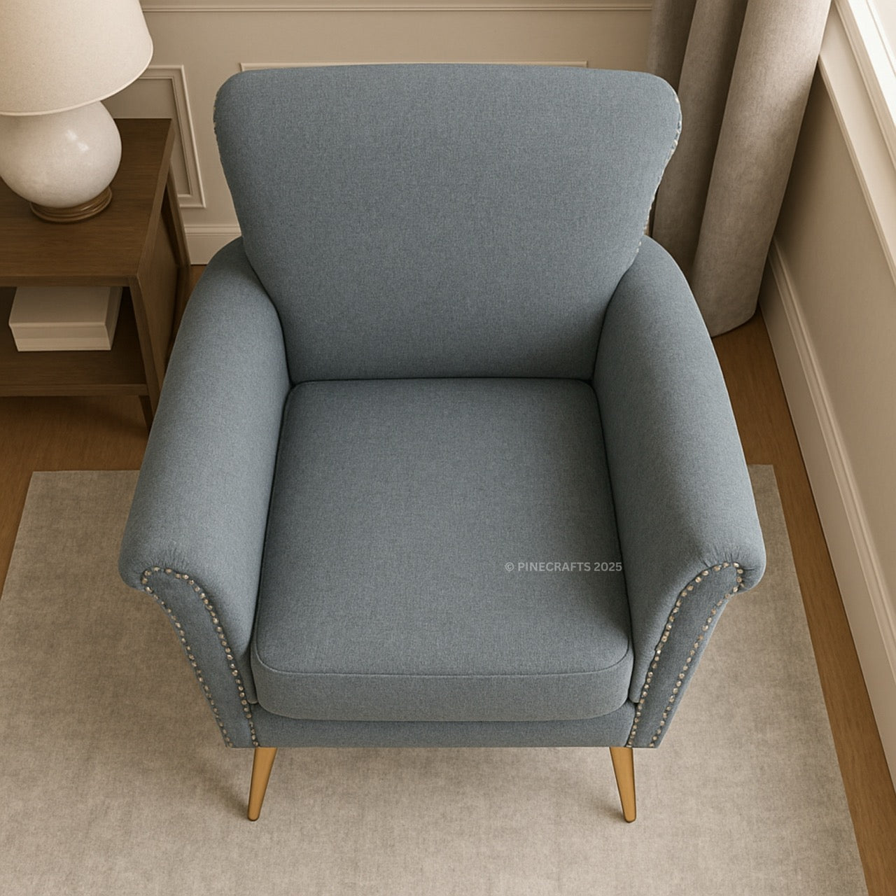 Gray armchair in a room with a lamp and bookshelf.