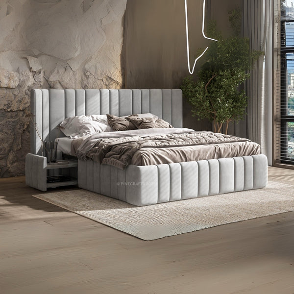 Gray upholstered bed in a modern bedroom with stone wall and plants.