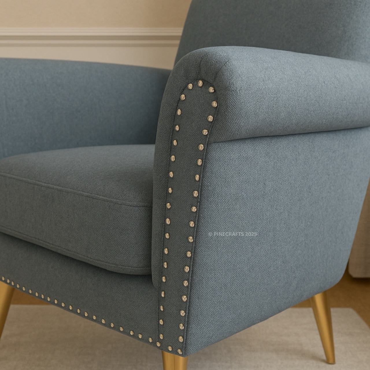 Gray armchair with nailhead trim on a beige background