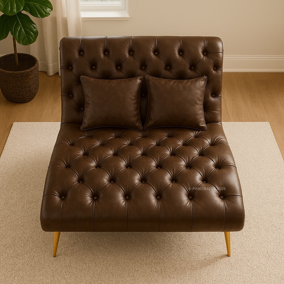 Brown leather tufted chaise lounge with two pillows in a room with a plant and window.