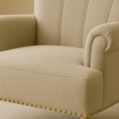 Beige armchair with gold nailhead trim on a beige background