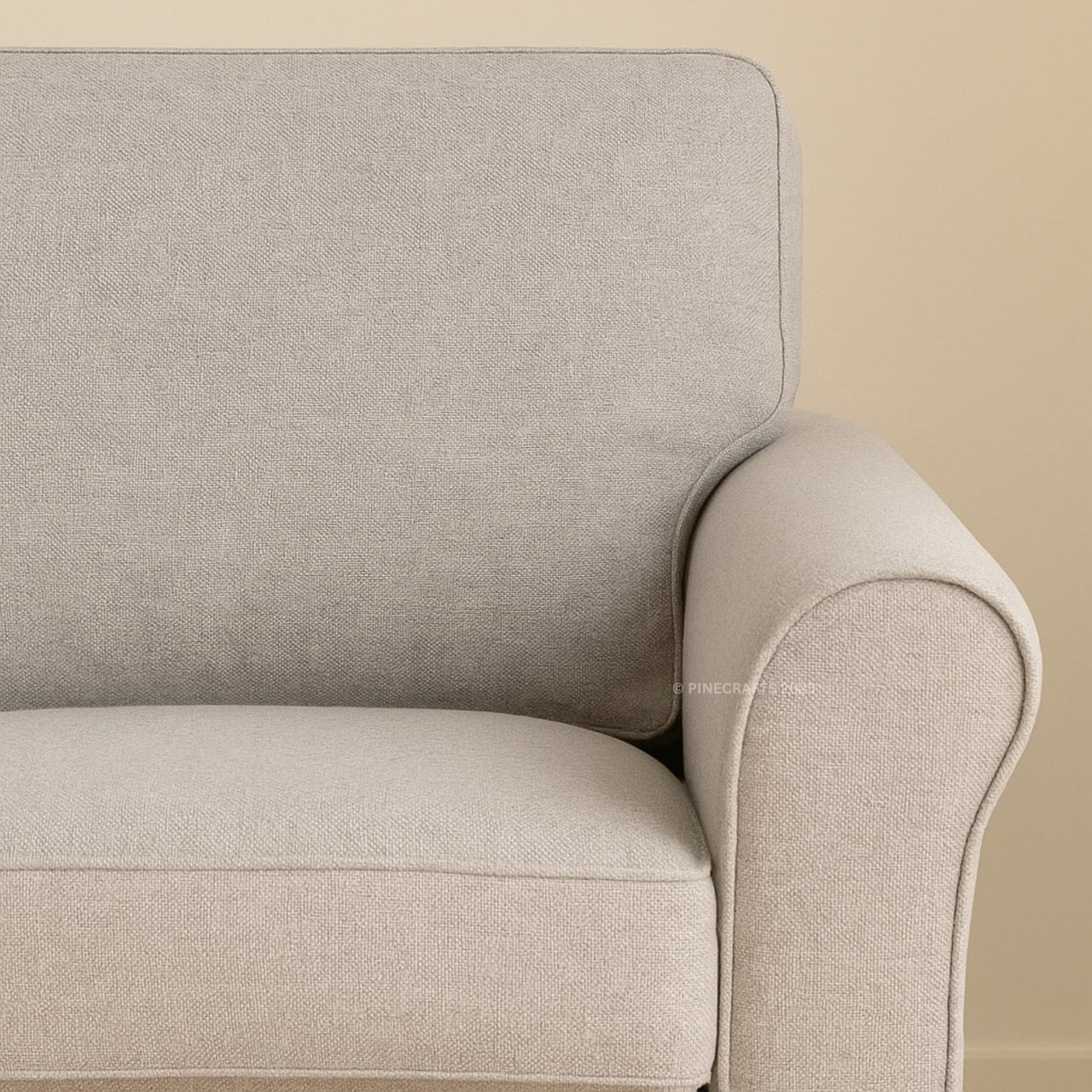 Close-up of a beige armchair against a beige wall