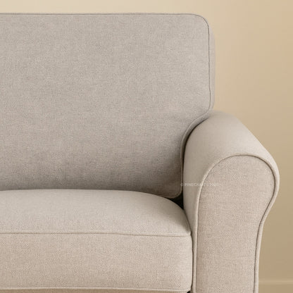 Close-up of a beige armchair against a beige wall