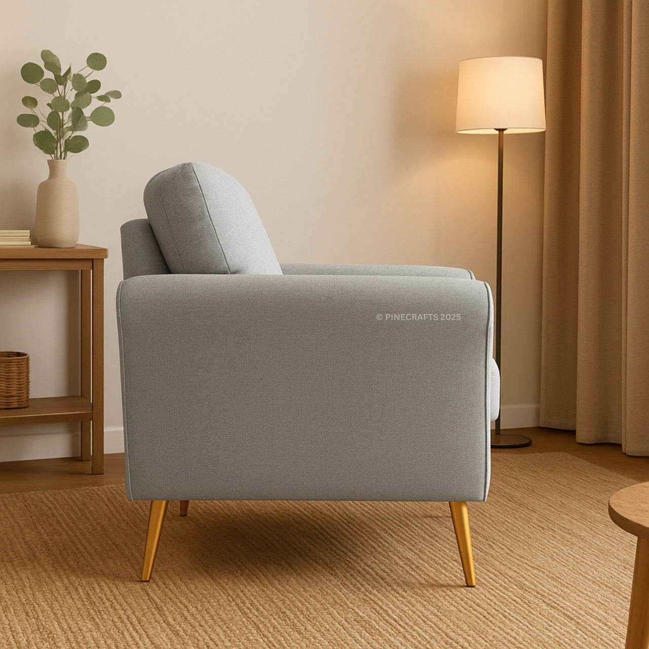 Gray armchair in a living room setting with a lamp and plant.