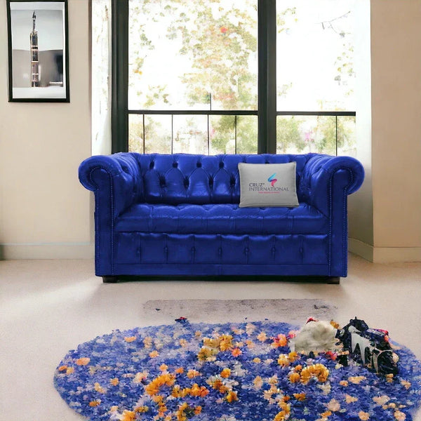 Blue tufted sofa with CRUZ INTERNATIONAL pillow in modern living room, floral round rug in front.