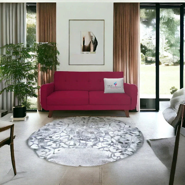 Modern living room with a maroon sofa, CRUZ INTERNATIONAL pillow, round rug, and indoor plant