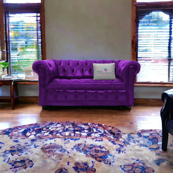 Purple tufted sofa in a cozy living room, CRUZ INTERNATIONAL pillow, wooden floor, vibrant rug
