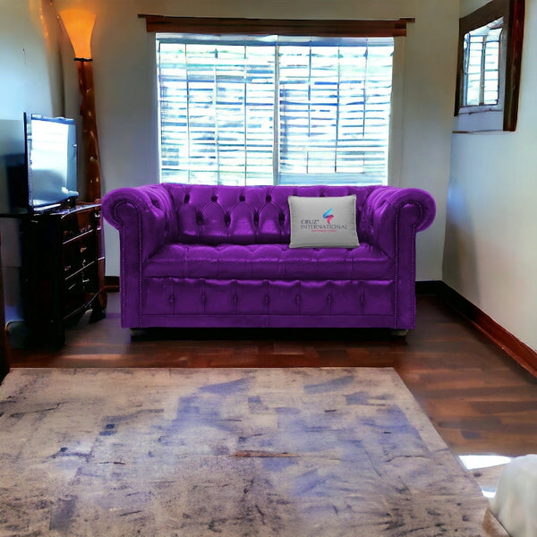 Purple tufted sofa with CRUZ INTERNATIONAL pillow in a modern living room with wooden floors