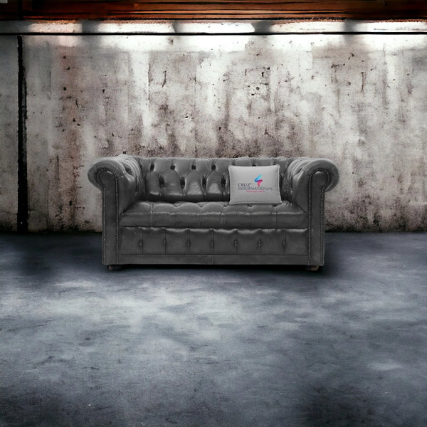 Silver tufted leather sofa with CRUZ INTERNATIONAL pillow in an industrial-style room