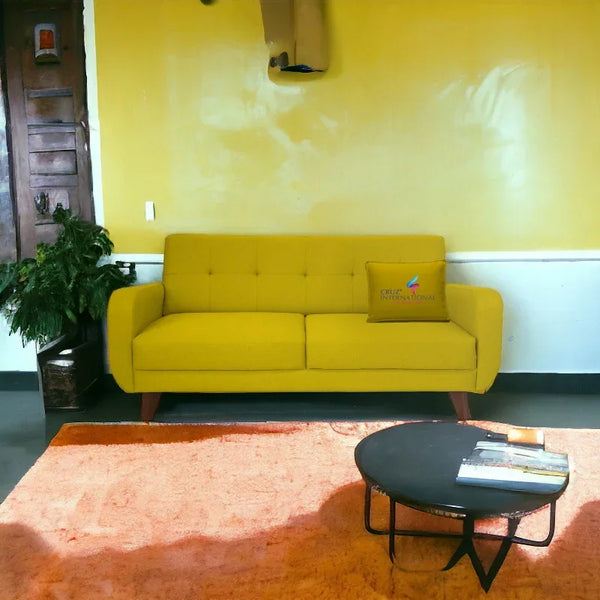 Modern yellow sofa with CRUZ INTERNATIONAL pillow, orange rug, black coffee table, indoor plant